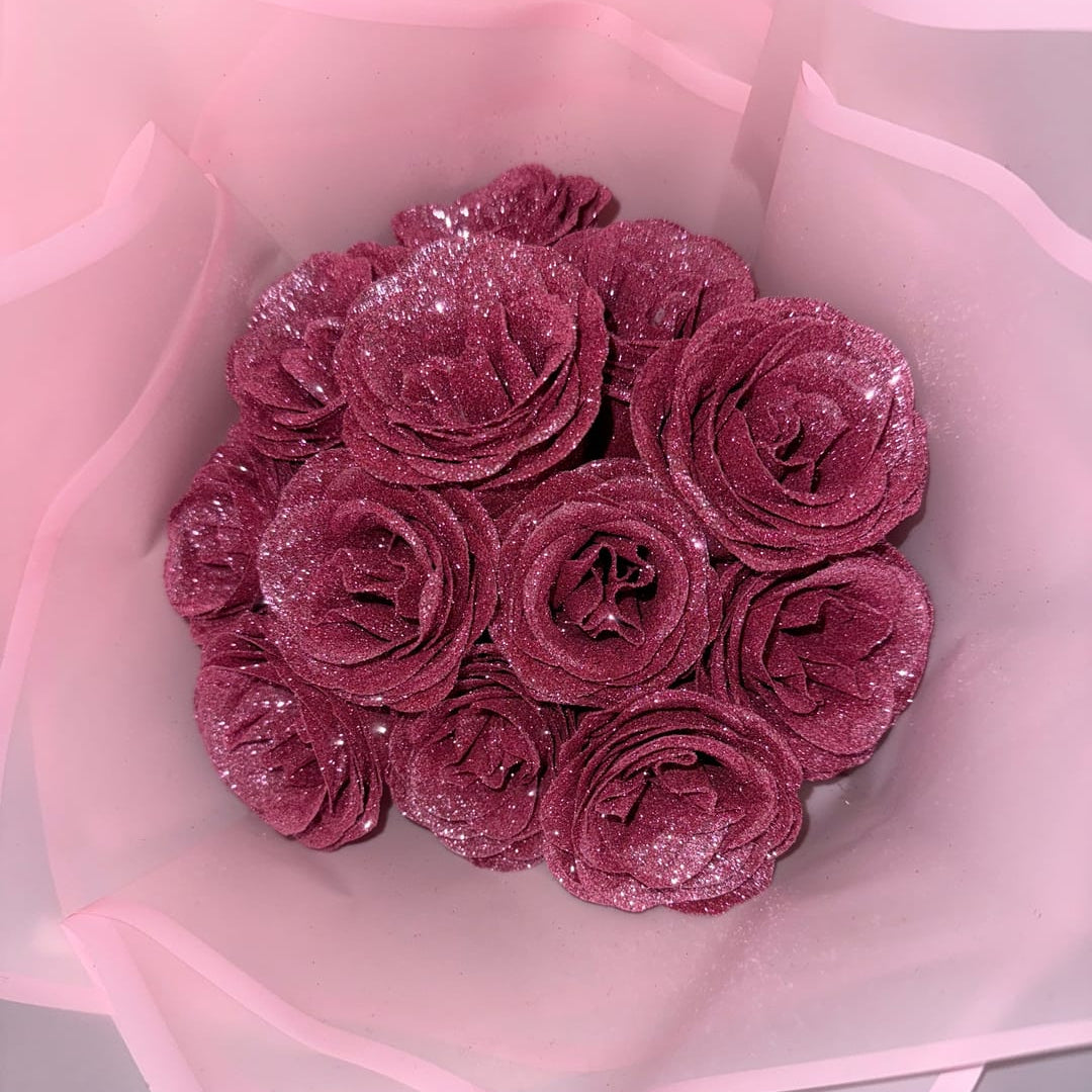 Bouquet of pink glittery roses in a clear cellophane wrap on a light gray background